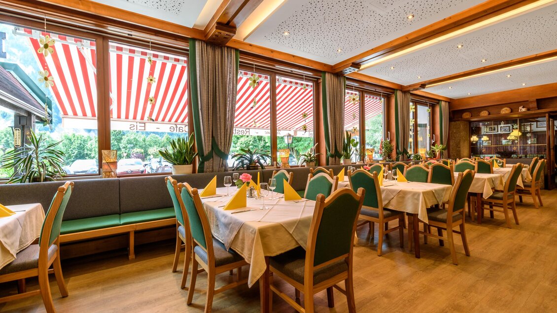 Ein gemütliches Restaurant mit Holzdekor und großen Fenstern. Die Tische sind ordentlich gedeckt und bieten einen Blick auf den Garten. | © Hotel Taferne