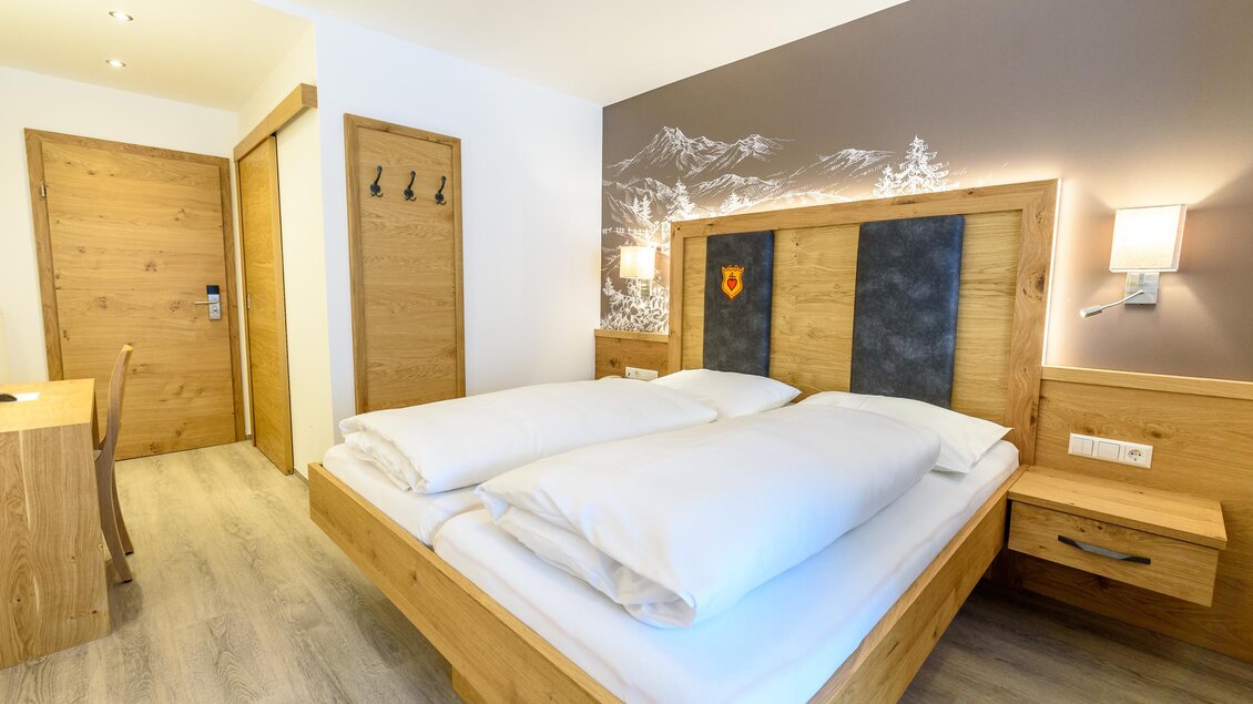 Ein modernes Schlafzimmer mit einem großen Doppelbett und Holzdetails. Die Wände sind in neutralen Farben gehalten, und der Raum wirkt hell und einladend. | © Hotel Taferne