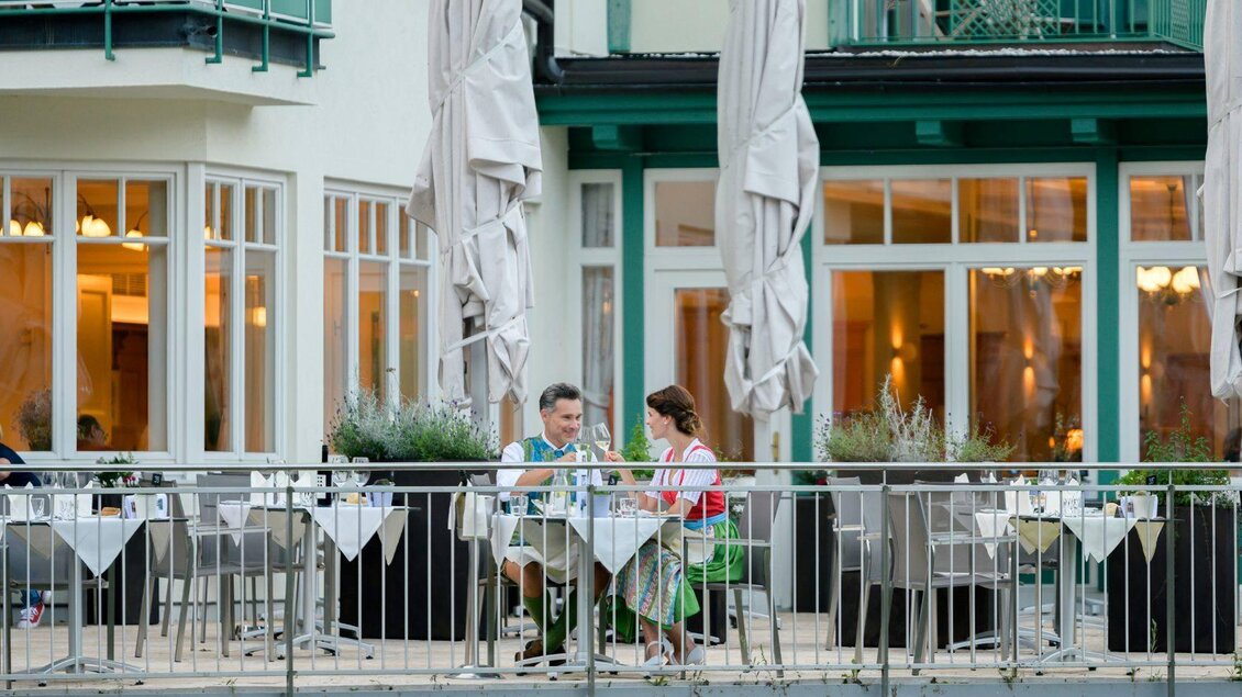 Ein Paar sitzt an einem Tisch auf der Terrasse eines Restaurants. Sie genießen ein Essen in einer angenehmen Atmosphäre mit Blick auf die Einrichtung im Hintergrund. | © Karl Steinegger