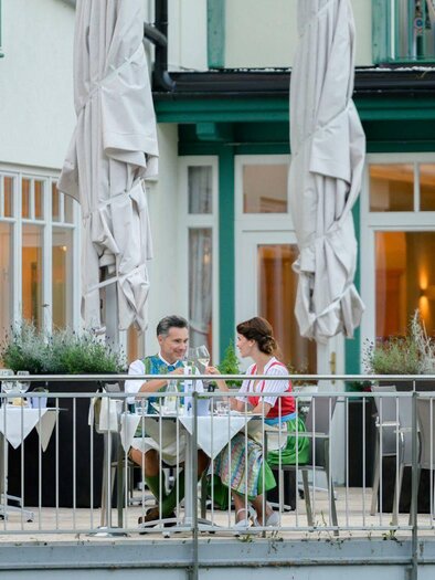 Ein Paar sitzt an einem Tisch auf der Terrasse eines Restaurants. Sie genießen ein Essen in einer angenehmen Atmosphäre mit Blick auf die Einrichtung im Hintergrund. | © Karl Steinegger