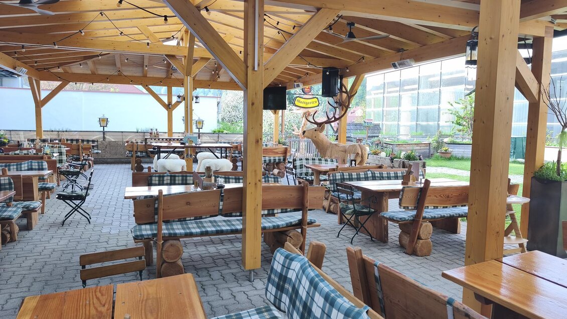 Ein gemütliches Restaurant mit Holzveranda und Tischen im Freien. Die Einrichtung hat ein rustikales Design mit karierten Tischtüchern. | © Brauhaus Murau