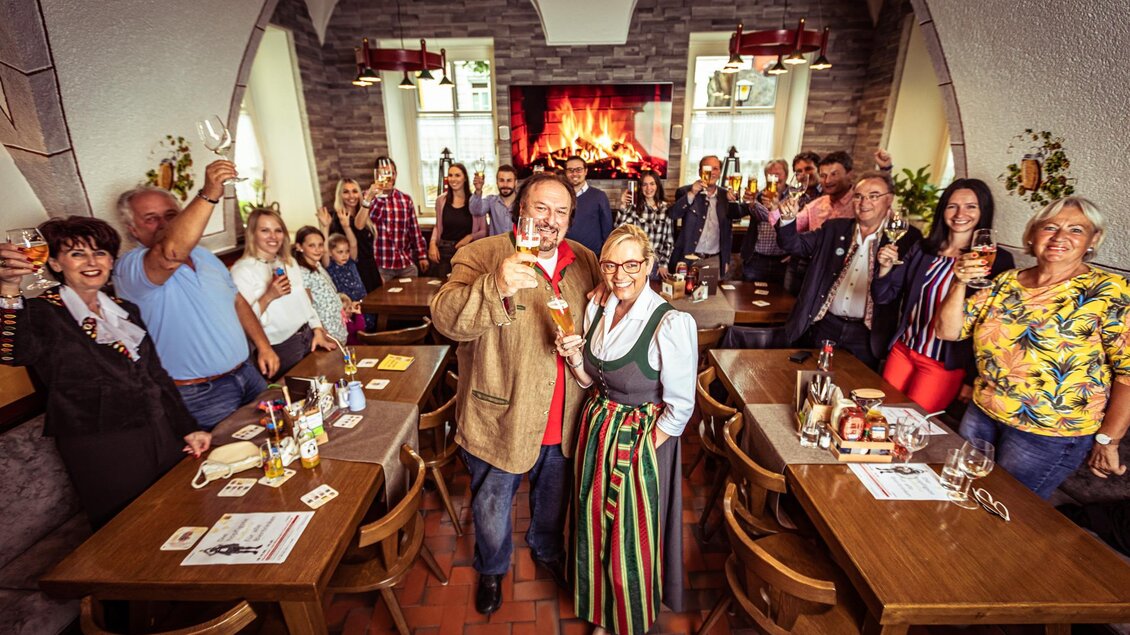 Eine fröhliche Versammlung von Menschen in einem gemütlichen Restaurant. Alle heben ihre Gläser und feiern zusammen. | © Hotel Brauhaus zu Murau