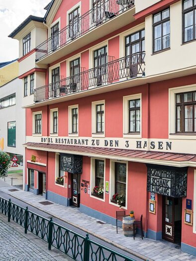 A charming restaurant named "Hotel Restaurant zu den 3 Hasen". The facade is brightly painted and there are pretty flowers at the windows. | © Rudy Dellinger