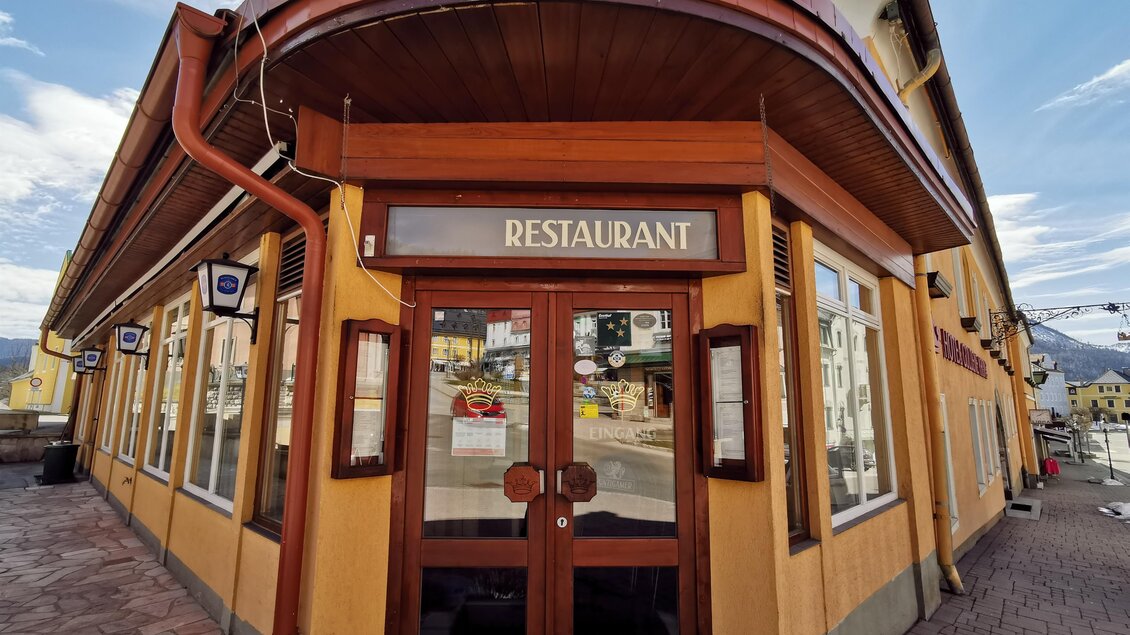 Ein einladendes Restaurant mit einer markanten Holztür. Die Fassade ist in einem warmen Gelbton mit großen Fenstern gestaltet. | © TV Hochsteiermark / Brigitte Digruber