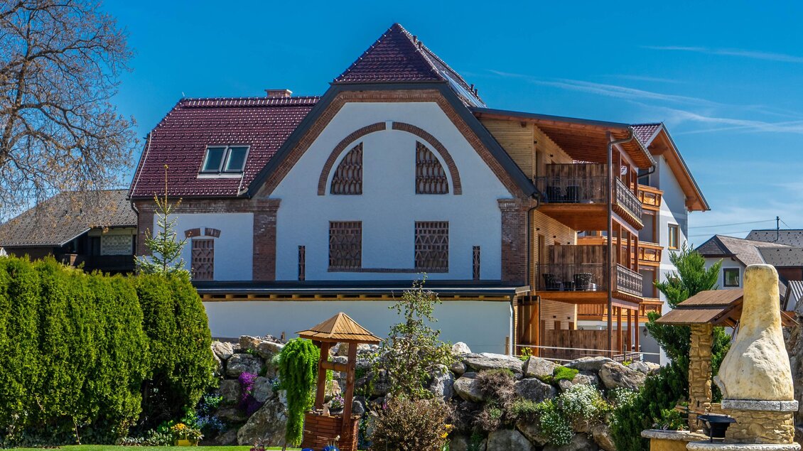 Ein modernes Haus mit zwei Etagen und Balkonen. Der Garten ist gepflegt und hat schöne Pflanzen sowie einen kleinen Pavillon. | © Hotel Restaurant Perschler