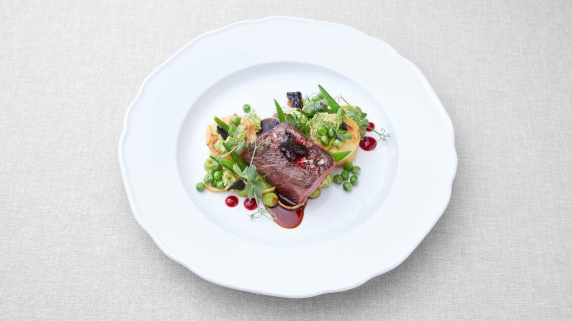 Ein kunstvoll angerichteter Teller mit einem Stück Fleisch, umgeben von buntem Gemüse und einer Sauce. Das Gericht ist geschmackvoll dekoriert und wirkt sehr ansprechend. | © Tauroa GmbH