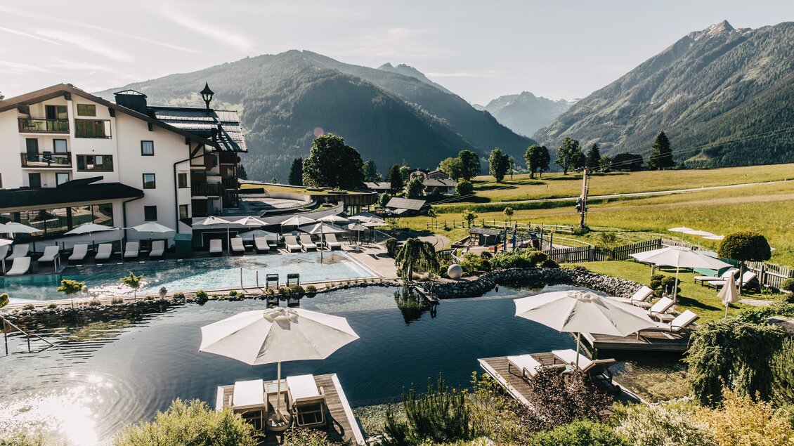 Ein elegantes Hotel mit einem Pool, umgeben von Bergen und grünen Wiesen. Sonnige Liegen und Schirme laden zur Entspannung ein. | © Hotel Schwaigerhof
