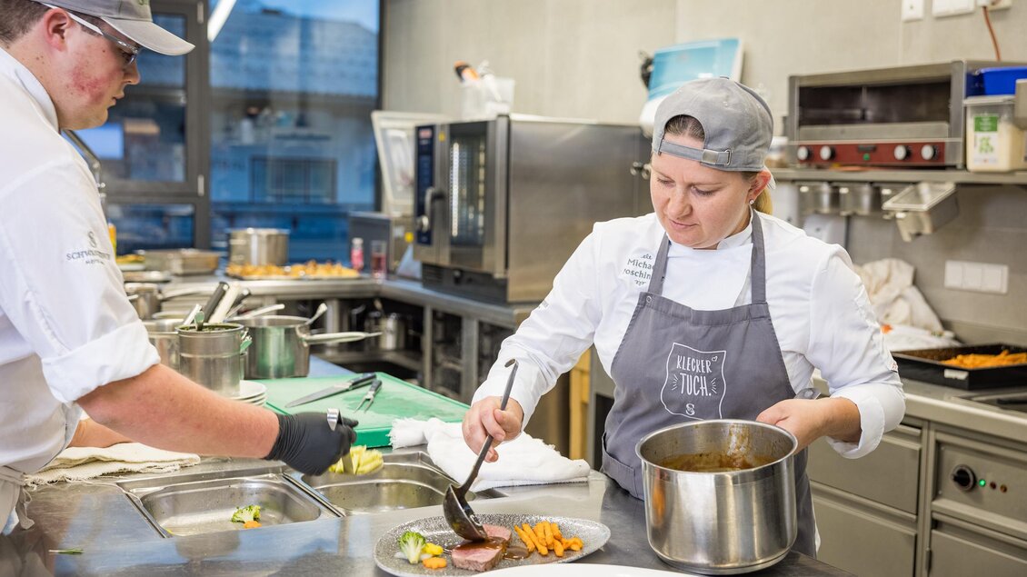 Zwei Köche arbeiten in einer modernen Küche. Der Mittelpunkt ist das Anrichten von Gerichten auf einem Teller. | © Netzwerk Kulinarik wildbild