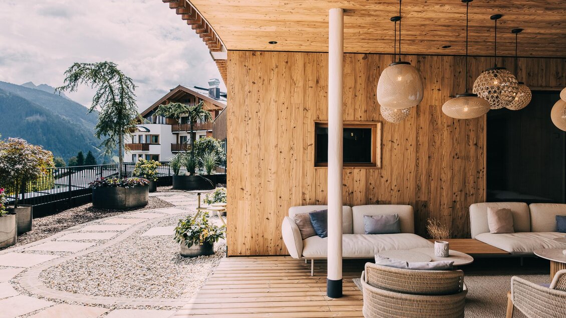 Ein gemütlicher Wohnraum mit Holzverkleidung und modernen Möbeln. Im Hintergrund sind Berge und Pflanzen zu sehen. | © Hotel Schwaigerhof