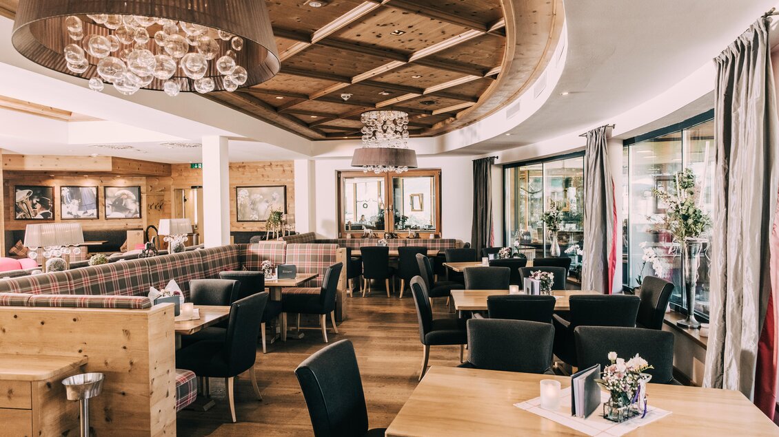 Ein gemütliches Restaurant mit Holzmöbeln und eleganter Beleuchtung. Die große Fensterfront sorgt für viel Tageslicht und eine einladende Atmosphäre. | © Hotel Schwaigerhof