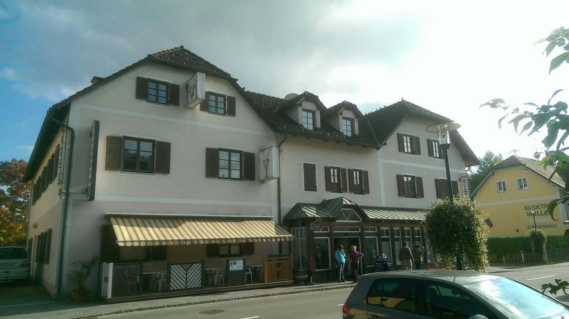 Ein traditionelles Gebäude mit mehreren Fenstern und einem Vordach. Die Fassade ist in hellen Farben gehalten, und es stehen einige Personen davor. | © Hotel Seltenriegel