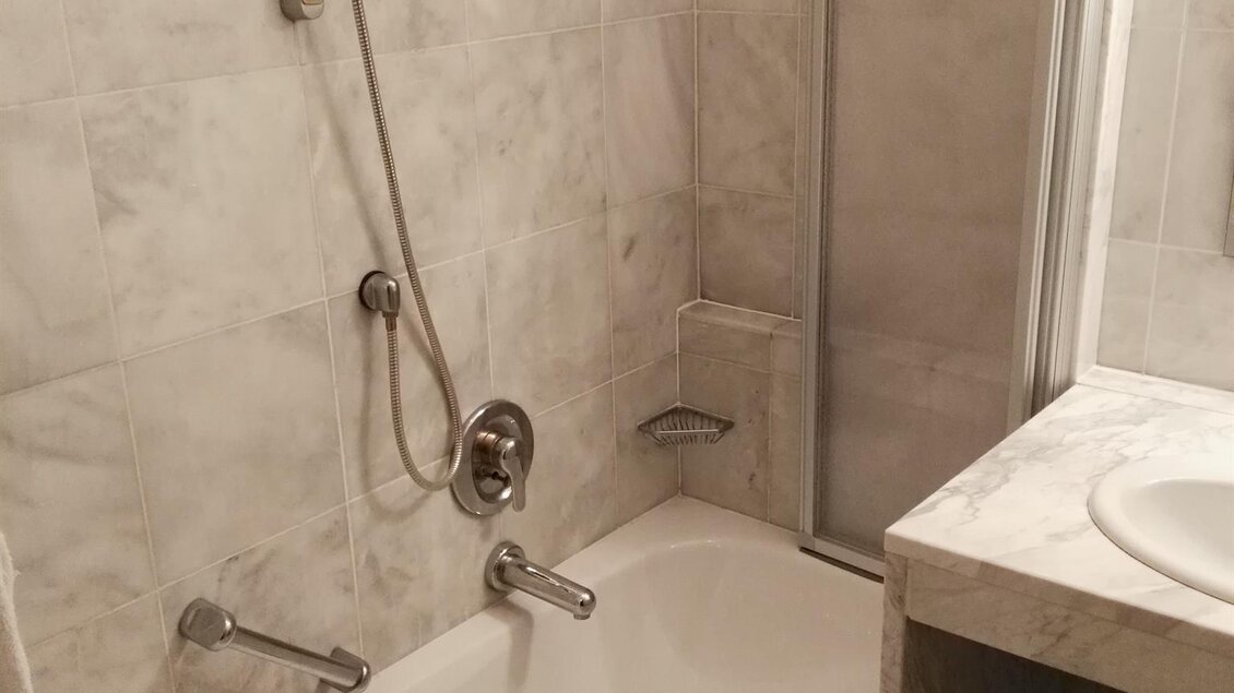 Ein Badezimmer mit einer Badewanne und Dusche. Die Wände sind mit grauen Fliesen verkleidet. | © Hotel Seltenriegel