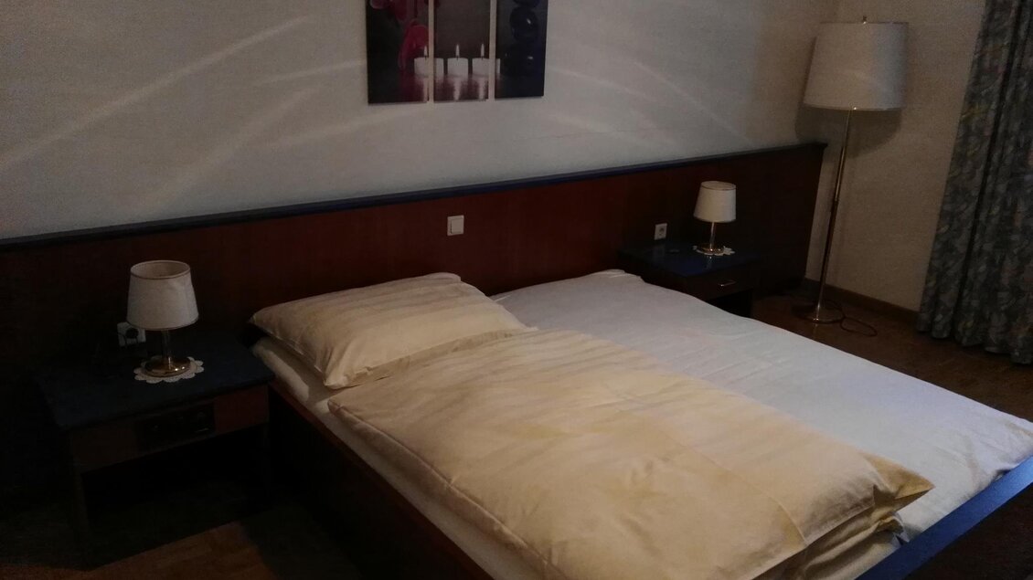 Ein einfaches Schlafzimmer mit einem Doppelbett und zwei Nachtischlampen. An der Wand hängt ein dekoratives Bild. | © Hotel Seltenriegel