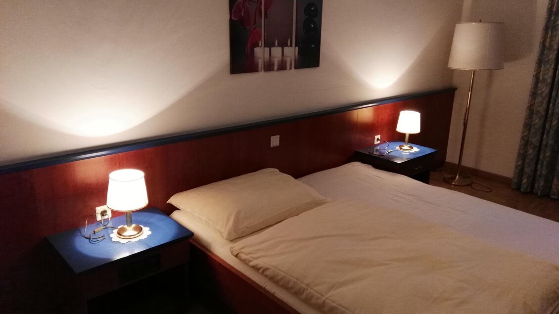 Ein gemütliches Schlafzimmer mit einem großen Bett und Nachttischen. Sanftes Licht von den Lampen schafft eine einladende Atmosphäre. | © Hotel Seltenriegel
