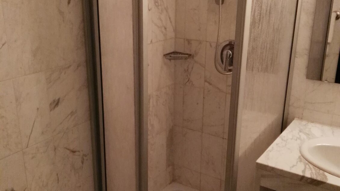 Eine moderne Dusche mit Glastüren in einem marmorierten Badezimmer. Der Waschtisch ist neben der Dusche sichtbar. | © Hotel Seltenriegel