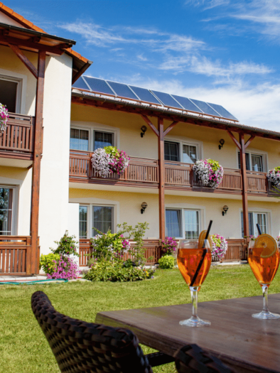 A quiet guesthouse with blooming balconies and a beautiful garden. On a table are two glasses with drinks, surrounded by an inviting atmosphere. | © Teuschler-Mogg