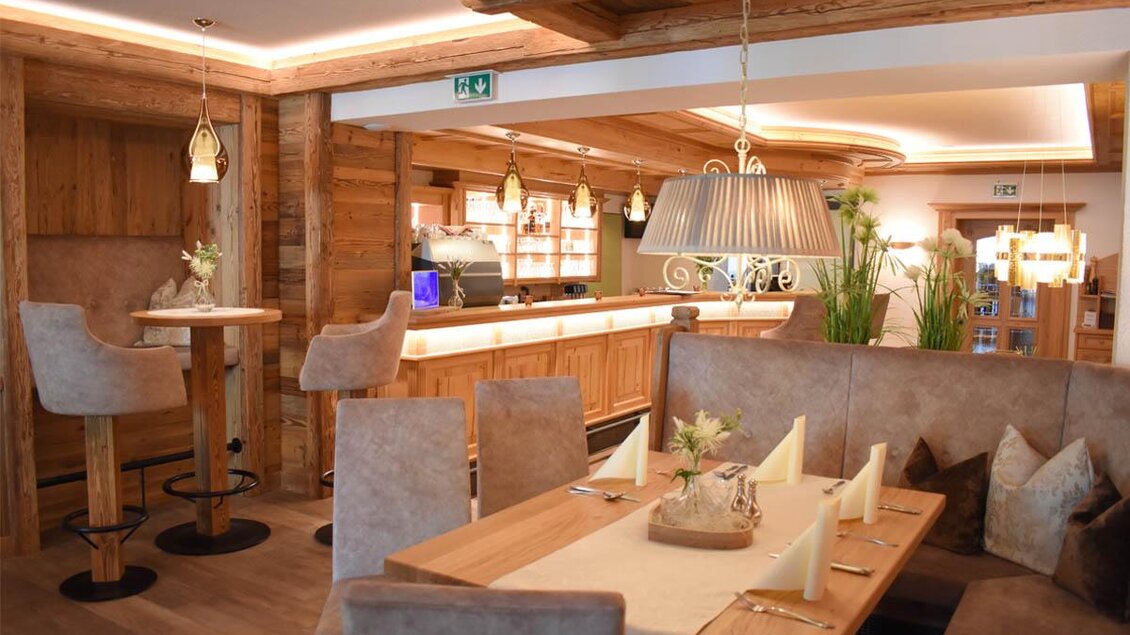 Ein gemütliches Restaurant mit Holzdekor und warmem Licht. Tische sind elegant gedeckt und die Bar ist gut sichtbar im Hintergrund. | © Desiree Zwanzleitner