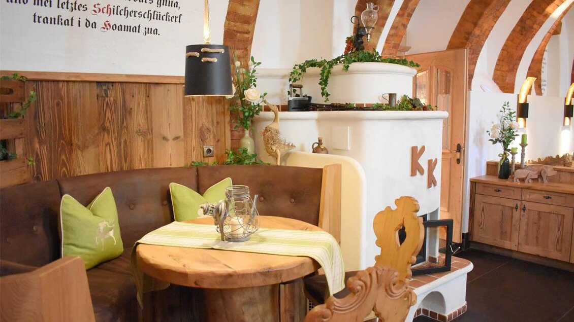 Ein gemütlicher Gastraum mit Holzmöbeln und einer runden Tafel. Der Raum hat traditionelle Architektur mit einem hellen Farbkonzept und dekorativen Pflanzen. | © Desiree Zwanzleitner