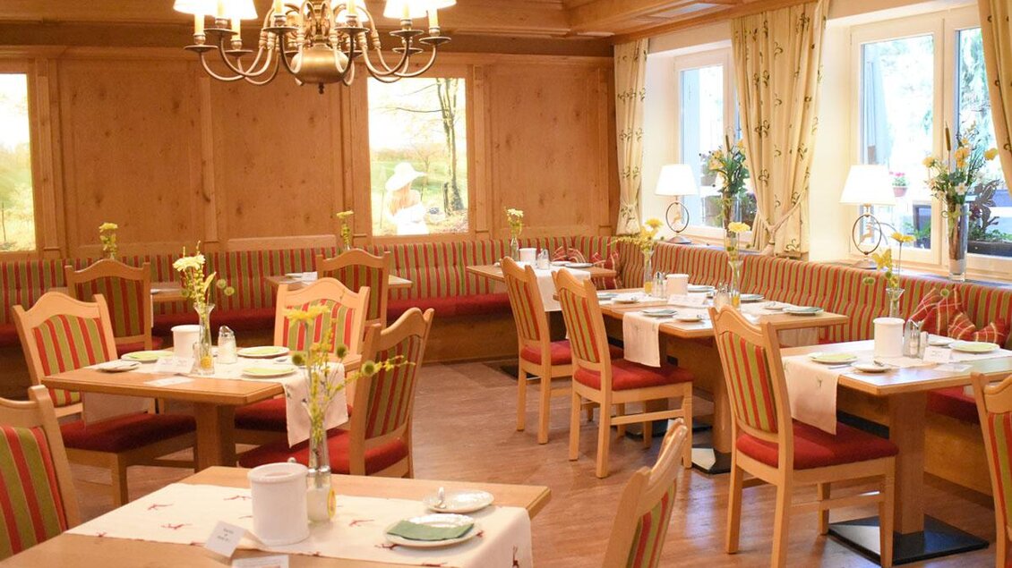 Ein einladendes Restaurant mit Holzmöbeln und gemütlichen Tischen. Die Fenster lassen viel Licht herein und sind mit Blumen dekoriert. | © Desiree Zwanzleitner