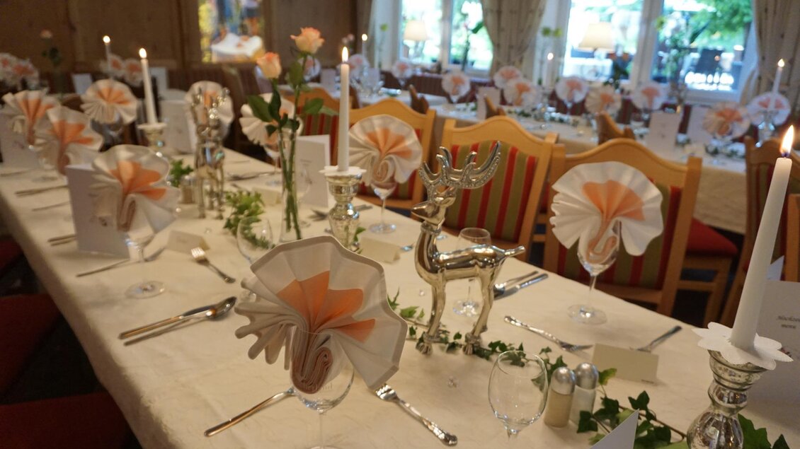 Ein elegant gedeckter Tisch mit weißer Tischdecke, Kerzen und dekorativen Servietten in sanften Farben. Die Atmosphäre ist festlich und einladend. | © Kloepferkeller