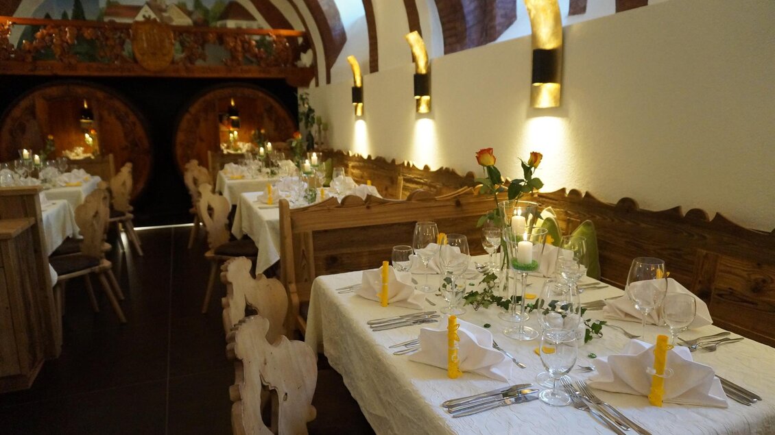 Ein gemütliches Restaurant mit holzernen Tischen und dekorierten Tischen. Sanfte Beleuchtung und frische Blumen schaffen eine einladende Atmosphäre. | © Kloepferkeller