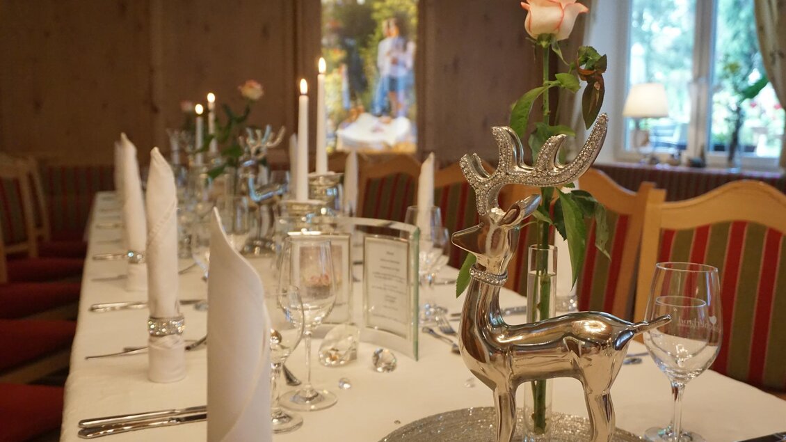 Ein festlich gedeckter Tisch mit Kerzen, Gläsern und einem silbernen Rentier als Dekoration. Im Hintergrund ist ein heller Raum mit Fenster und ansprechender Beleuchtung. | © Kloepferkeller