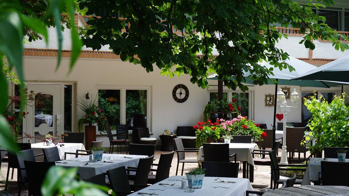 Ein einladendes Restaurant mit gedeckten Tischen unter Bäumen. Blumen und eine entspannte Atmosphäre laden zum Verweilen ein. | © Kloepferkeller