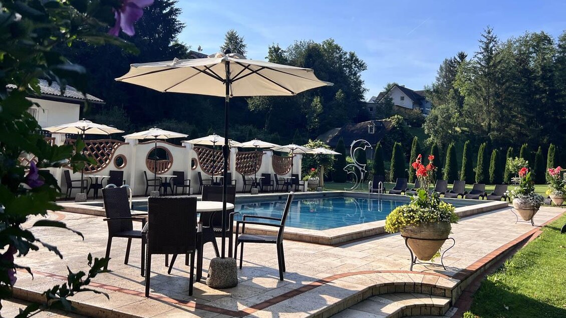 Ein schöner Außenbereich mit einem Swimmingpool und Sonnenschirmen. Die Umgebung ist grün und einladend, perfekt zum Entspannen. | © Desiree Zwanzleitner
