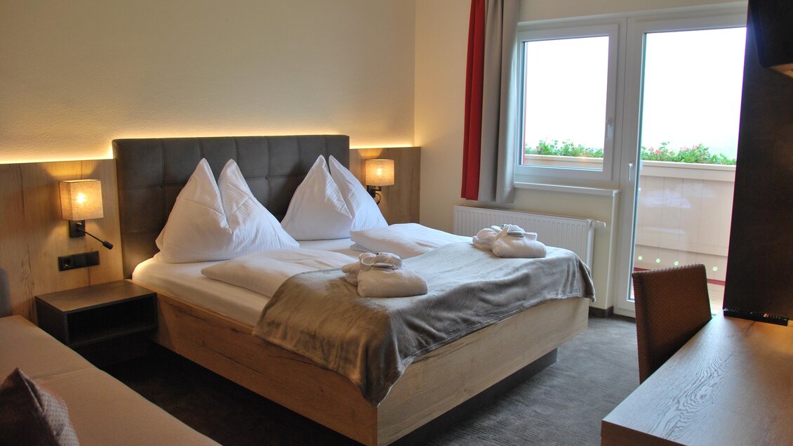 Ein modernes Schlafzimmer mit einem Doppelbett und zwei Kopfkissen. Der Raum hat große Fenster, die viel Tageslicht hereinlassen. | © Algo