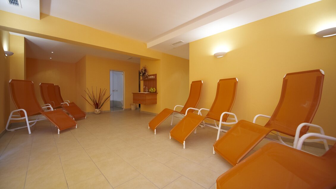 Ein entspannender Raum mit orangefarbenen Liegen und einer warmen Wandfarbe. Ideal zum Entspannen und Erholen. | © Algo