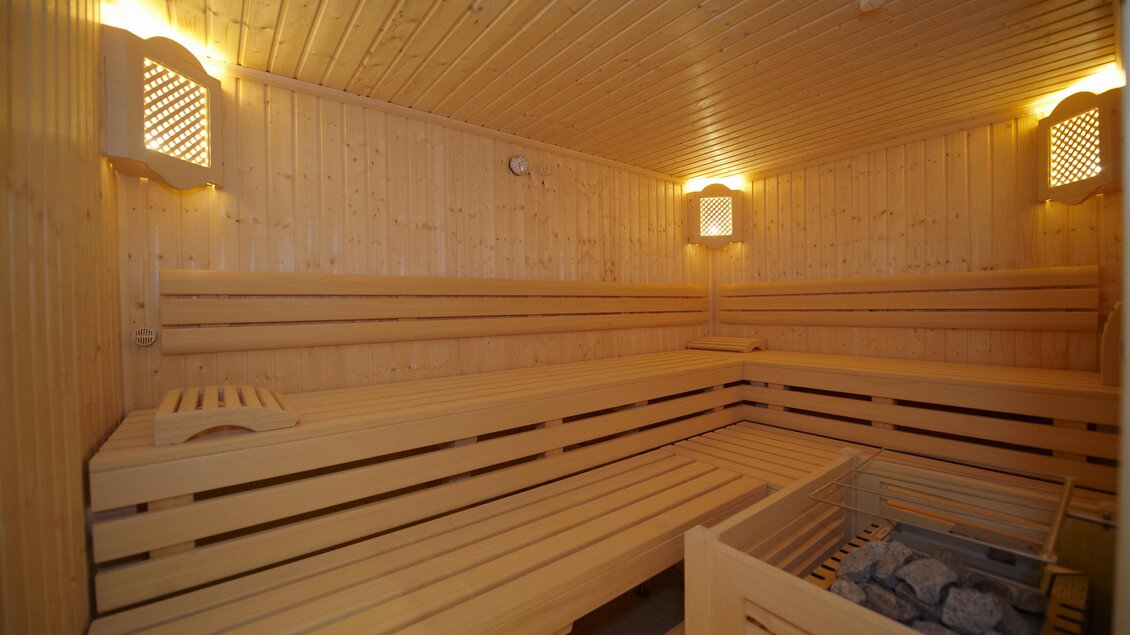 Ein gemütlicher Innenraum einer Sauna aus Holz. Die Wände sind mit warmem Licht beleuchtet und es gibt Platz zum Entspannen. | © Algo