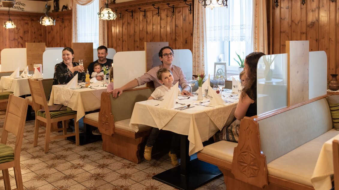 Man sieht eine Familie mit einem kleinen Kind am weiß gedeckten Tisch sitzen.  | © Hotel-Restaurant Schwarzer Adler