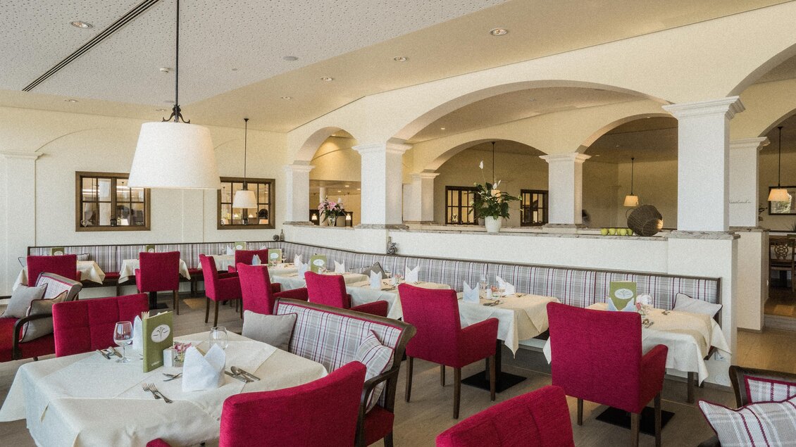 Ein stilvolles Restaurant mit roten Stühlen und eleganten Tischdecken. Die Architektur ist hell und modern, mit großen Fenstern und offenen Bereichen. | © Heilthermen Resort BW