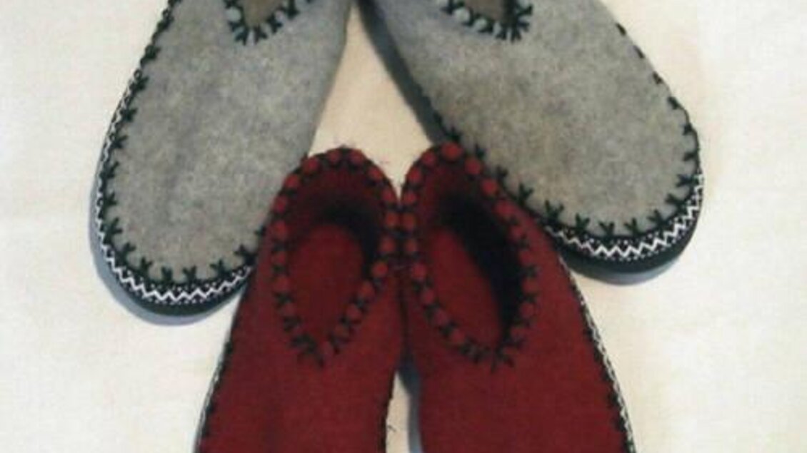 Zwei Paare von Hausschuhen aus Filz, eines grau und eines rot. Sie sind handgefertigt und haben eine dekorative Naht. | © Huber Strick- und Walkwaren