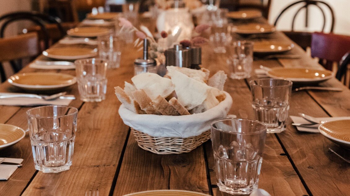 Ein gedeckter Tisch mit Tellern und Gläsern. In der Mitte befindet sich ein Korb mit frischem Brot. | © Hummel Graz