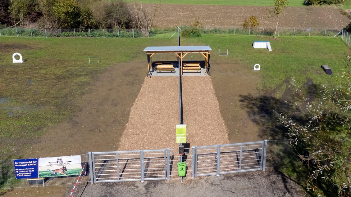 Ein Trainingsplatz mit einem langen Sandbereich und einer überdachten Plattform. Im Hintergrund sind einige Hindernisse und eine weitläufige Wiese zu sehen. | © © Stadtgemeinde Feldbach