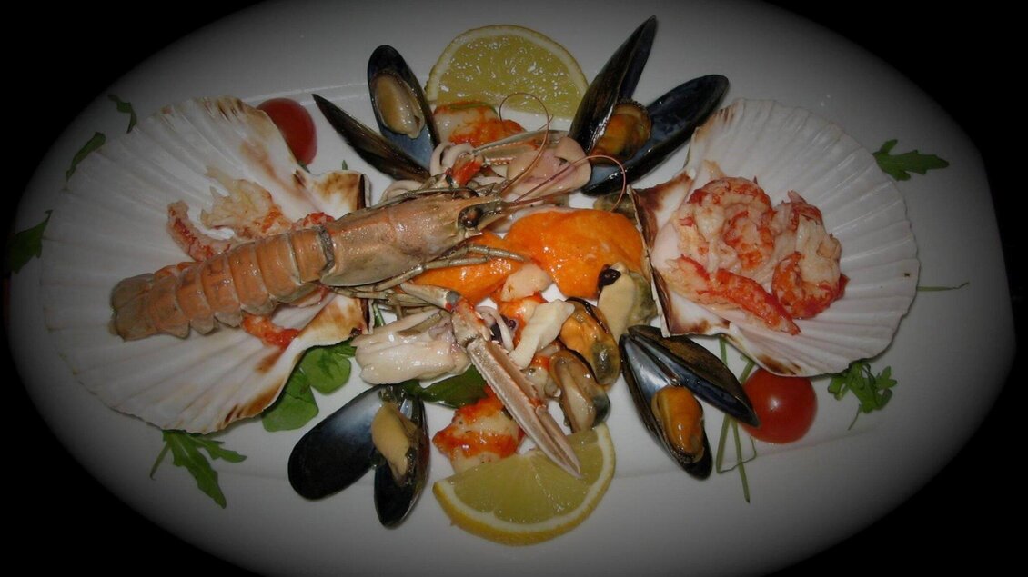 Ein köstlicher Meeresfrüchte-Teller mit Garnelen, Muscheln und Jakobsmuscheln. Frisches Gemüse und Zitrone dekorieren das Gericht. | © Il Centro
