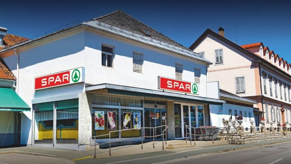 Ein SPAR-Markt in einer ruhigen Straße mit angrenzenden Gebäuden. Die Fassade ist hell und einladend, ideal für den Einkauf. | © Imbissstube Tschiltsch