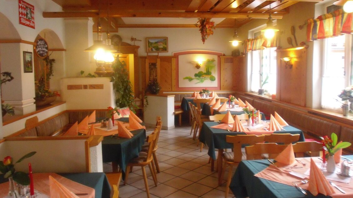 Wirtshaus mit Holzdecke, Sitzbänken, grün gedeckten Tischen und Deko. | © In's Pfandl