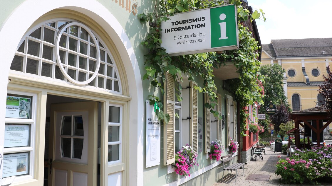 Ein Gebäude mit Schildern zur Touristeninformation. Die Fassade ist mit Pflanzen und Blumen geschmückt. | © TV Südsteiermark