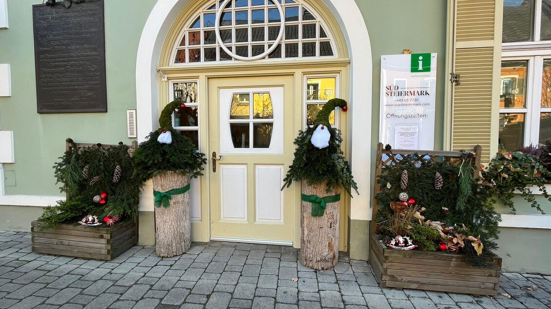 Eine hübsche Eingangstür mit dekorativen Pflanzenarrangements auf beiden Seiten. Die Pflanzen sind festlich geschmückt und verleihen dem Eingang einen einladenden Eindruck. | © TV Südsteiermark