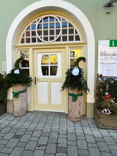 A beautiful front door with decorative plant arrangements on both sides. The plants are festively decorated and give the entrance an inviting impression. | © TV Südsteiermark