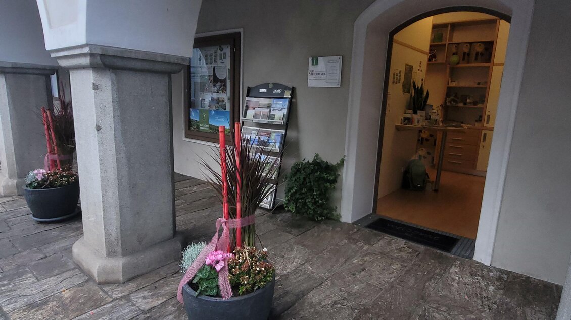 Ein Eingangsbereich mit Säulen und einer offenen Tür. Vor der Tür stehen große Pflanzen mit roten Dekorationen. | © TV Südsteiermark - Irene Löschnig