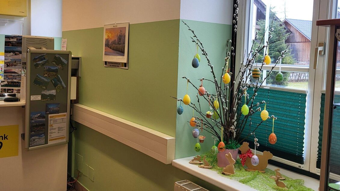 Ein Raum mit einer hellgrünen Wand und einem dekorierten Baum für Ostern. Der Baum ist mit bunten Eiern geschmückt und auf der Fensterbank liegen Papphasen und grüne Dekoration. | © Petra Kirchschlager