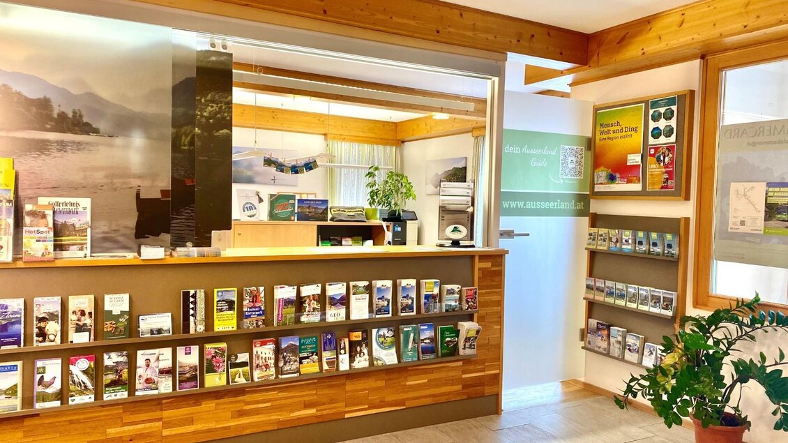 Ein einladender Empfangsbereich mit Holzdekor und Informationsmaterialien. Es gibt Regale mit Broschüren und eine gemütliche Atmosphäre. | © Bettina Scheck