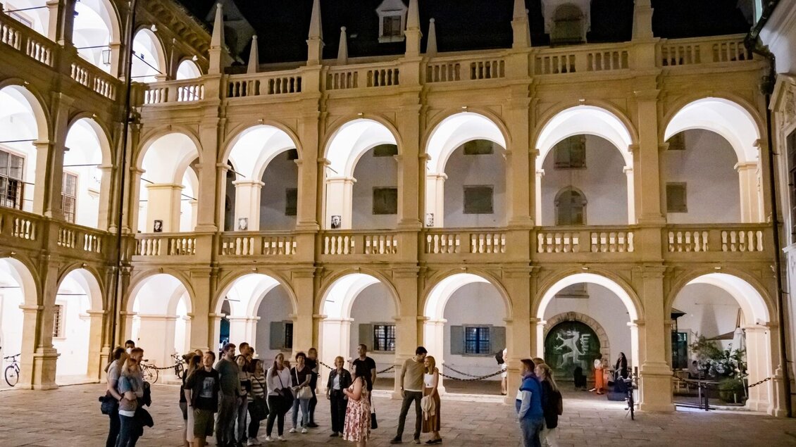 Besuchergruppe im beleuchteten Landhaushof Graz mit Arkaden bei Nacht | © Graz Tourismus-Werner Krug