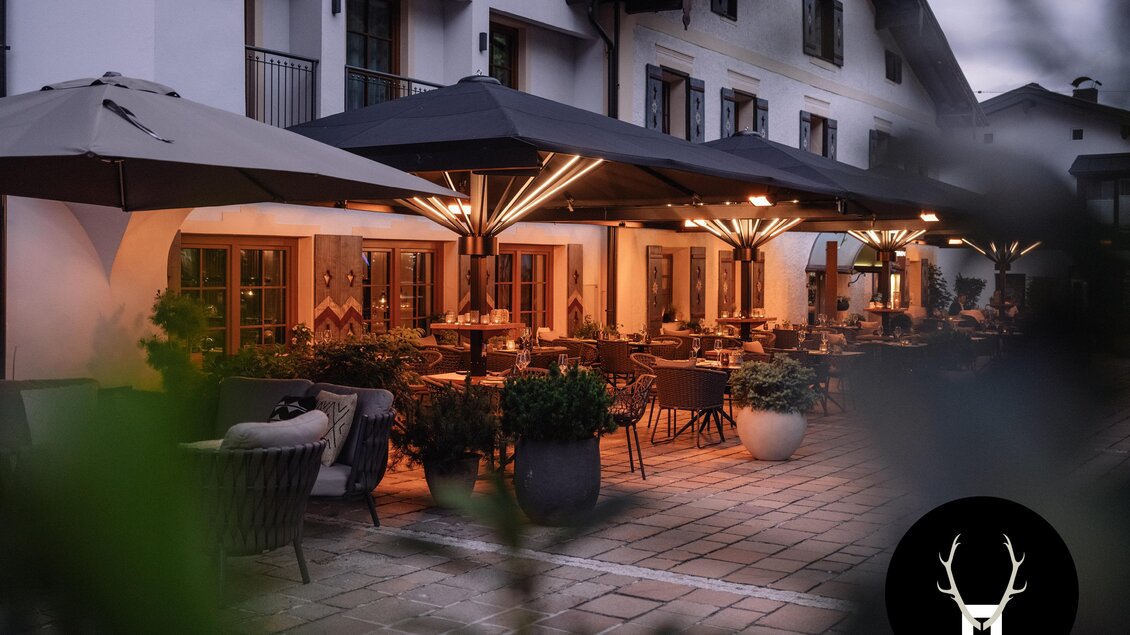 Eine gemütliche Terrasse mit modernen Möbeln und Sonnenschirmen. Die Umgebung ist ruhig und einladend, perfekt für einen entspannten Abend. | © JOHANN Schladming