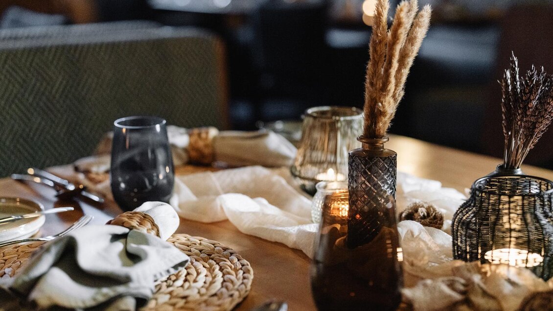 Ein schön gedeckter Tisch mit dekorativen Elementen und Kerzenlicht. Die Atmosphäre wirkt gemütlich und einladend. | © JOHANN Schladming