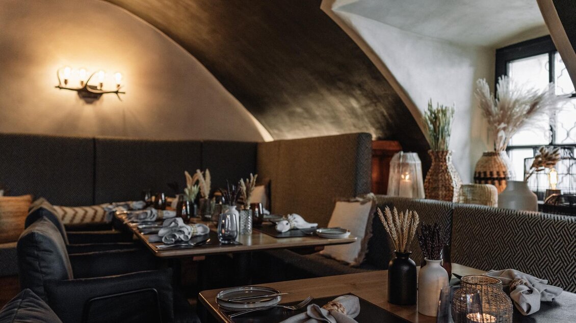 Ein stilvolles Restaurant mit gemütlichen Sitzecken und eleganter Tischdekoration. Die sanfte Beleuchtung schafft eine einladende Atmosphäre. | © JOHANN Schladming