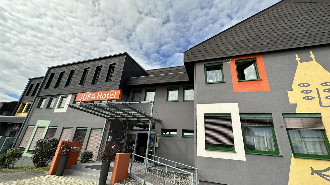 Ein modernes Hotelgebäude mit einer einladenden Fassade. Der Eingangsbereich ist gut gestaltet und lädt zum Verweilen ein. | © JUFA Hotels